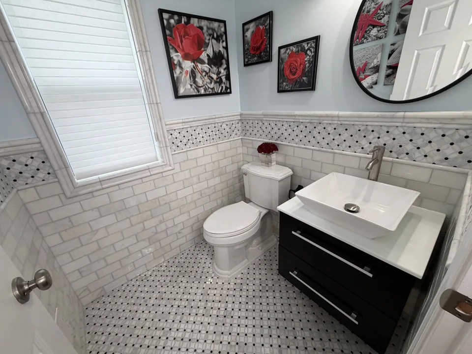 After: downstairs bathroom with white rectangular wall tile, a patterned border and floor, and a dark vanity with a vessel sink.