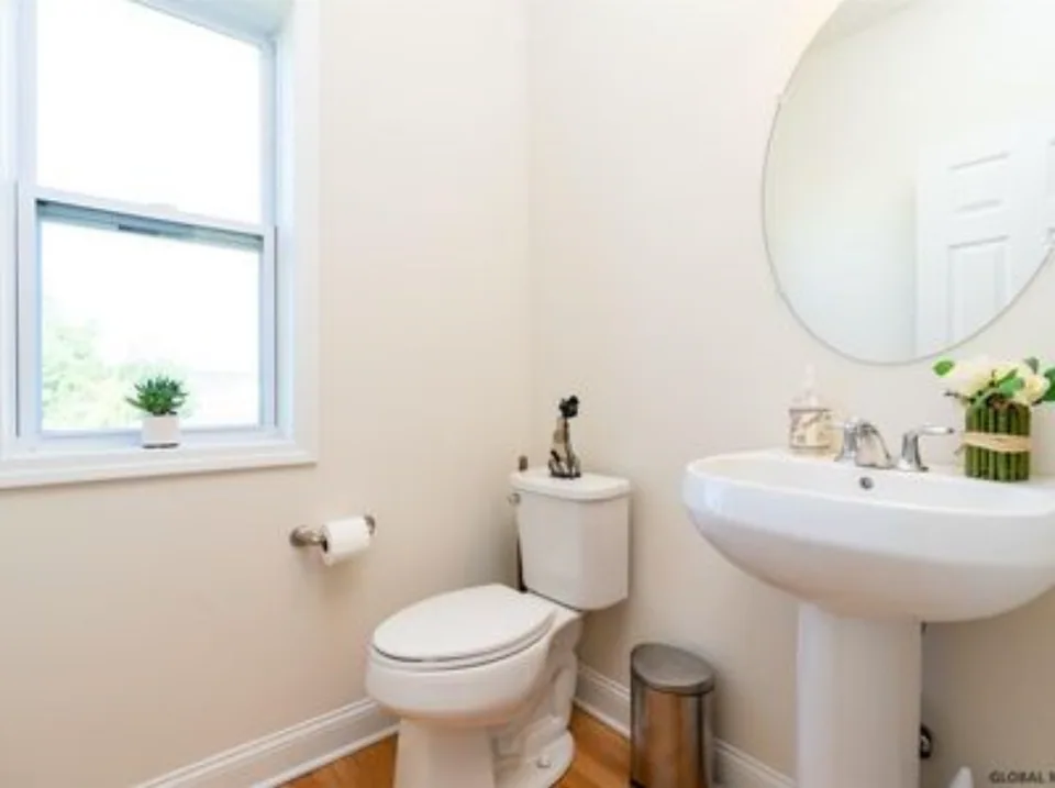 Before: downstairs bathroom with painted walls, a pedestal sink, and wood flooring.