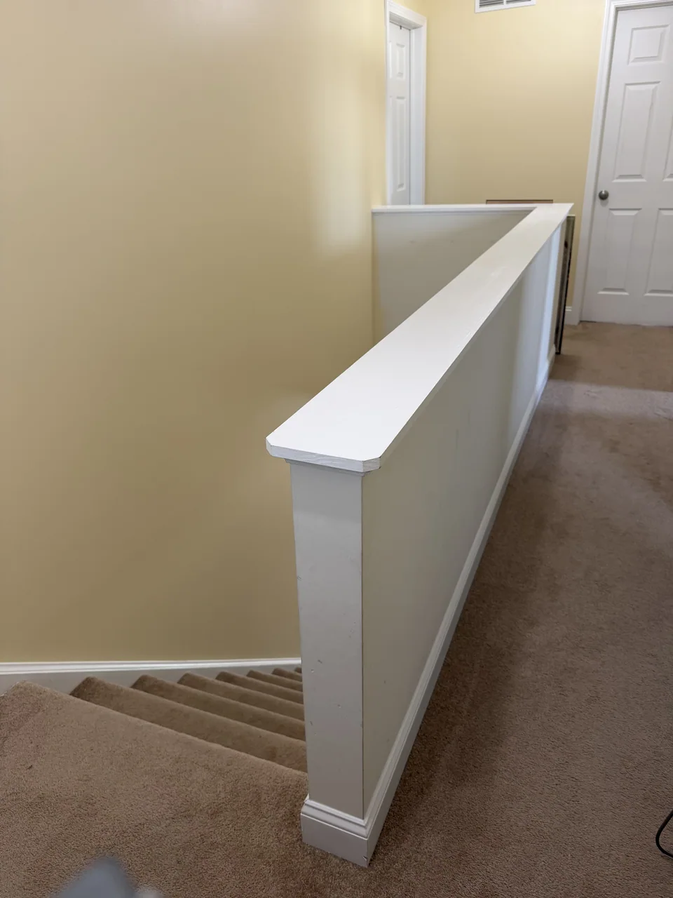Before: carpeted stairs and an upstairs landing enclosed by a painted half wall.