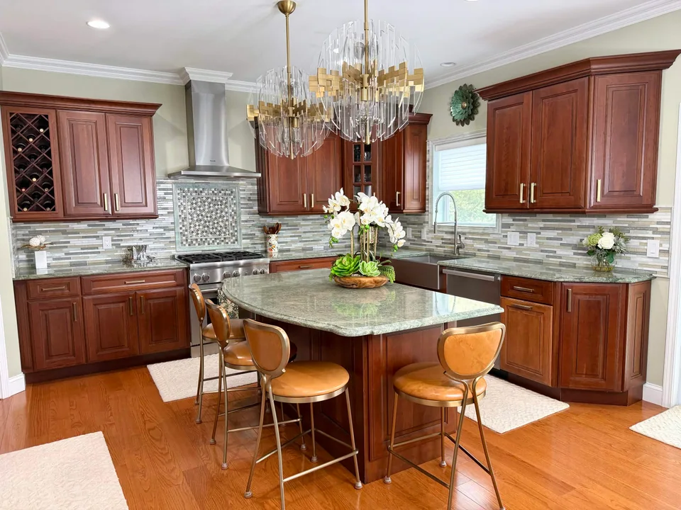 Kitchen with wood cabinets and a linear tile backsplash with a framed patterned panel behind the range.