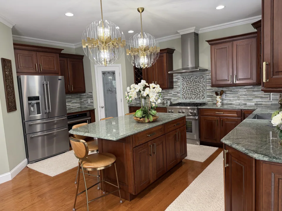 After: kitchen with a tiled backsplash and framed feature panel, installed appliances, an island, and pendant lights.